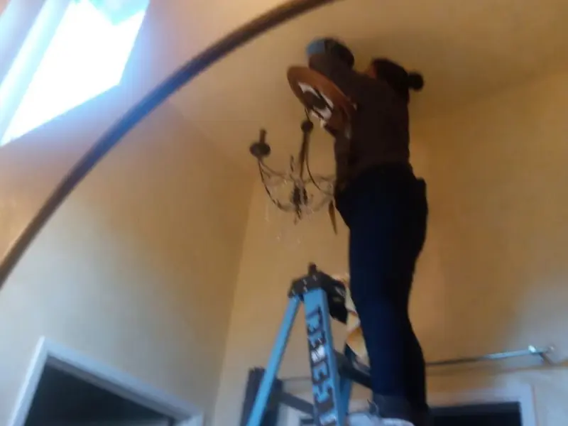 Electrician installing a chandelier in a Wilkshire Hills residence